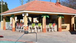 Uma área de estar coberta ao ar livre, com cadeiras e piscina.
