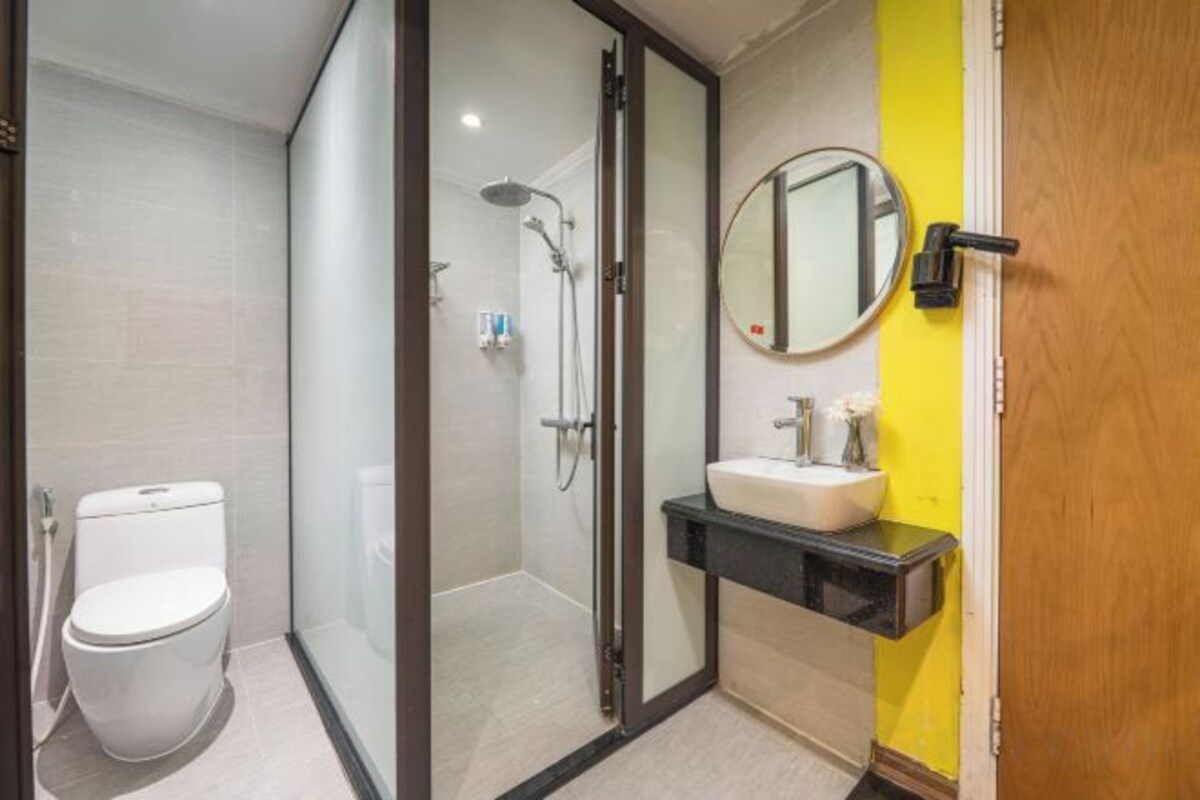 A modern bathroom with a glass-enclosed shower, a toilet, and a sink with a mirror.