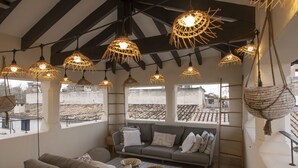 A cozy living room with a sofa, chairs, and hanging wicker lamps. - Ocho Suites & Kitchen (Palma de Mallorca)