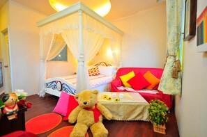 A room with a four-poster bed, a sofa, a teddy bear, and a small table with a vase of flowers. - Smile Orange Homestay (Dongshan)
