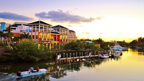 A waterfront hotel with multiple buildings, docked boats, and a calm river.