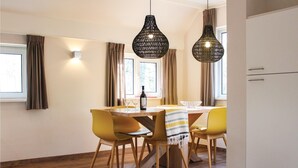 A dining area with a wooden table, yellow chairs, and black hanging lights. - Stunning home in Ommen with WiFi (Ommen)