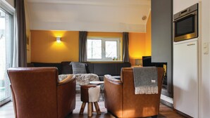 A modern living room with leather armchairs, a sofa, a small table, and a TV mounted on the wall. - Stunning home in Ommen with WiFi (Ommen)