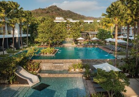 A resort pool area with a slide, lounge chairs, and umbrellas.