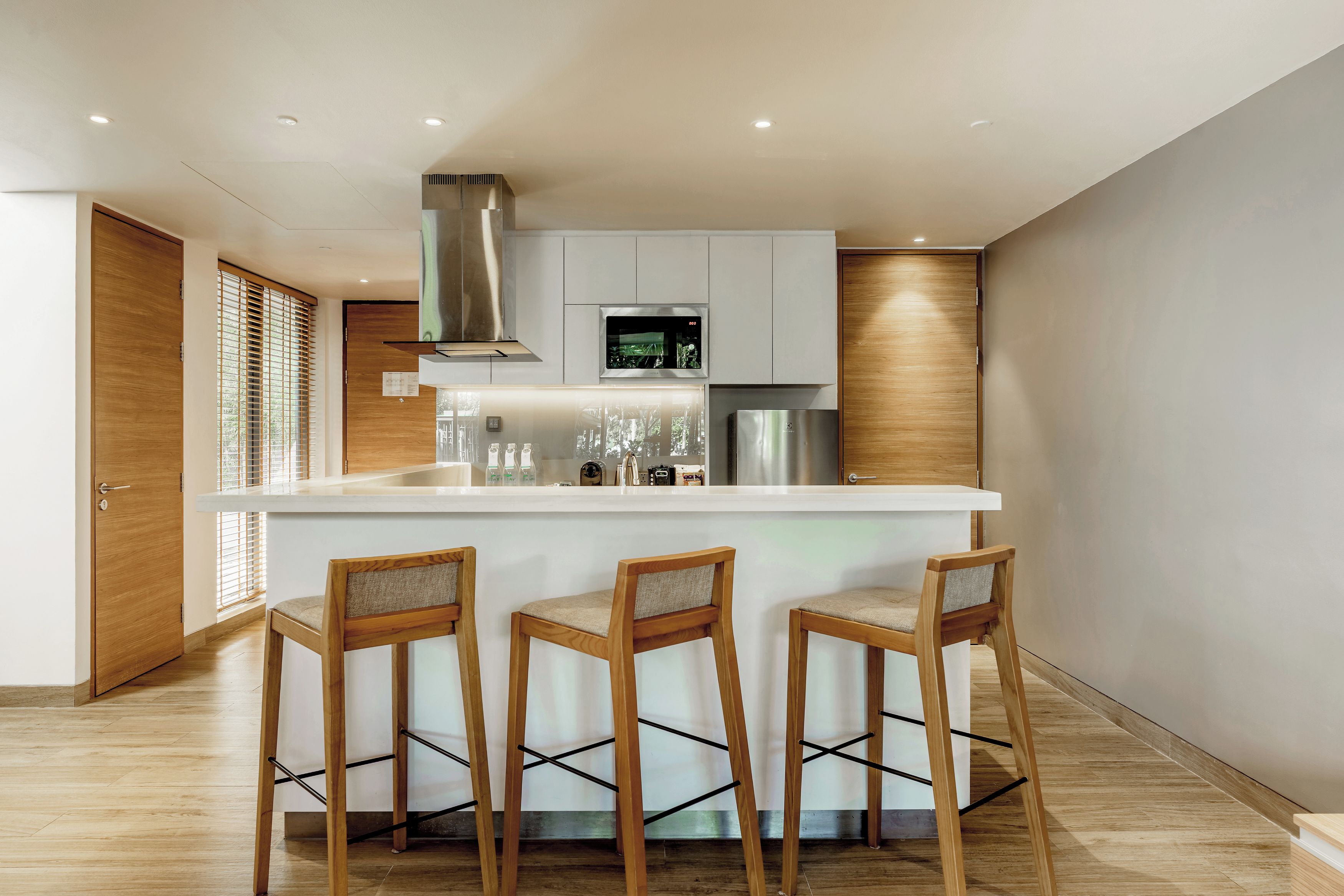 A modern kitchen with a central island, bar stools, and a stainless steel refrigerator.