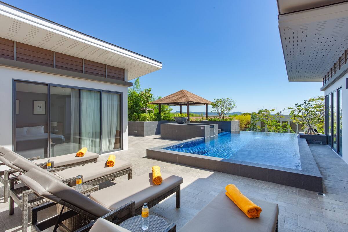 A modern outdoor pool area with lounge chairs, a hot tub, and a pergola.