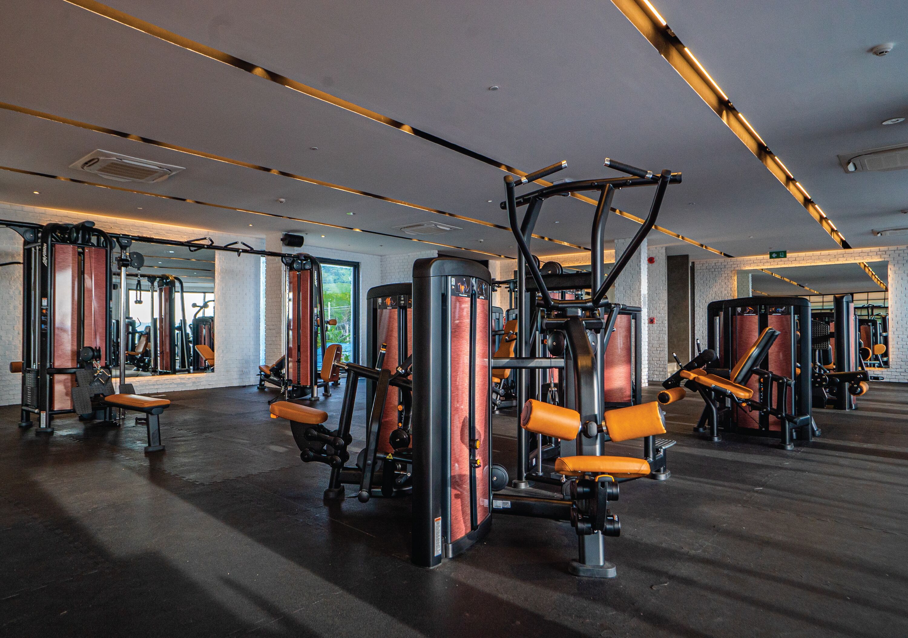 A gym with various exercise machines, benches, and mirrors.