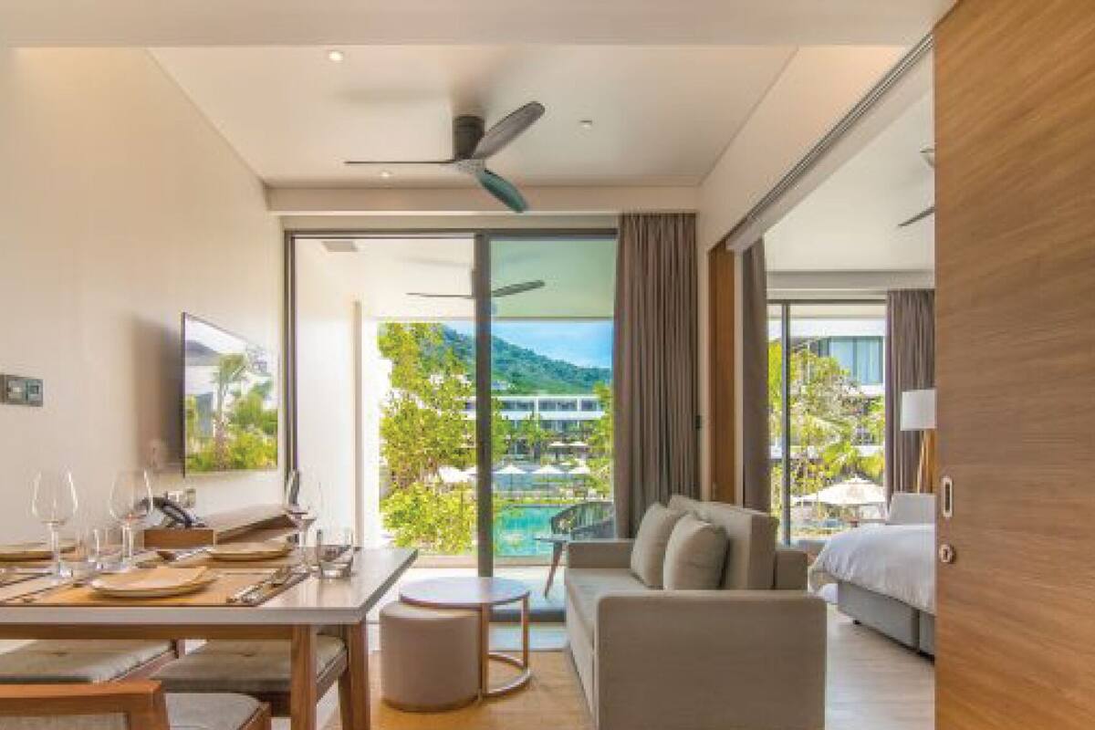 A modern hotel room with a dining area, a sofa, and a bed.