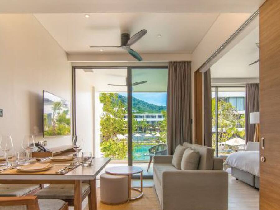 Una habitación de hotel moderna con zona de comedor, sofá y cama.