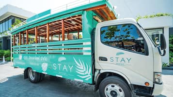 Un autobús STAY verde y blanco con bancos de madera, publicitando un resort con estilo de vida.