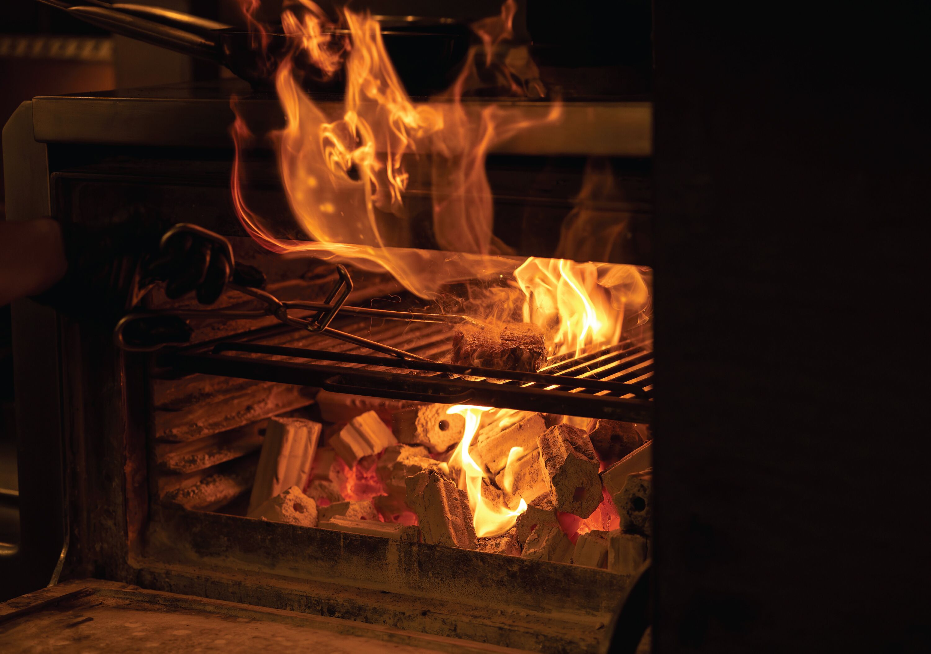 A grill with burning charcoal and flames.