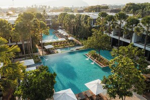Una gran piscina al aire libre rodeada de palmeras y edificios modernos.