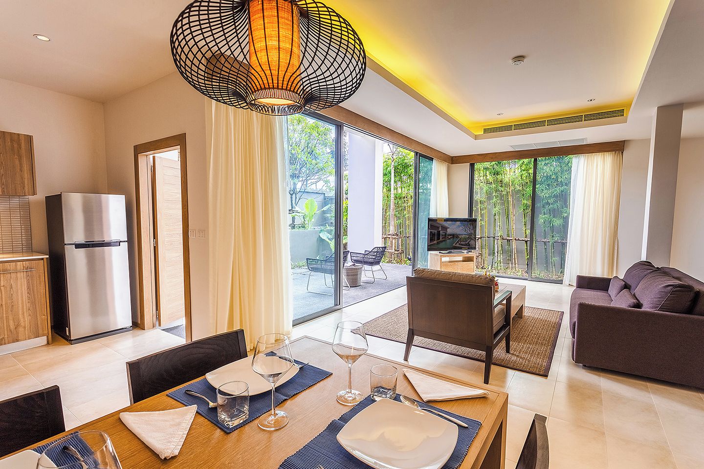 A modern living room with a dining area, a television, and a refrigerator.