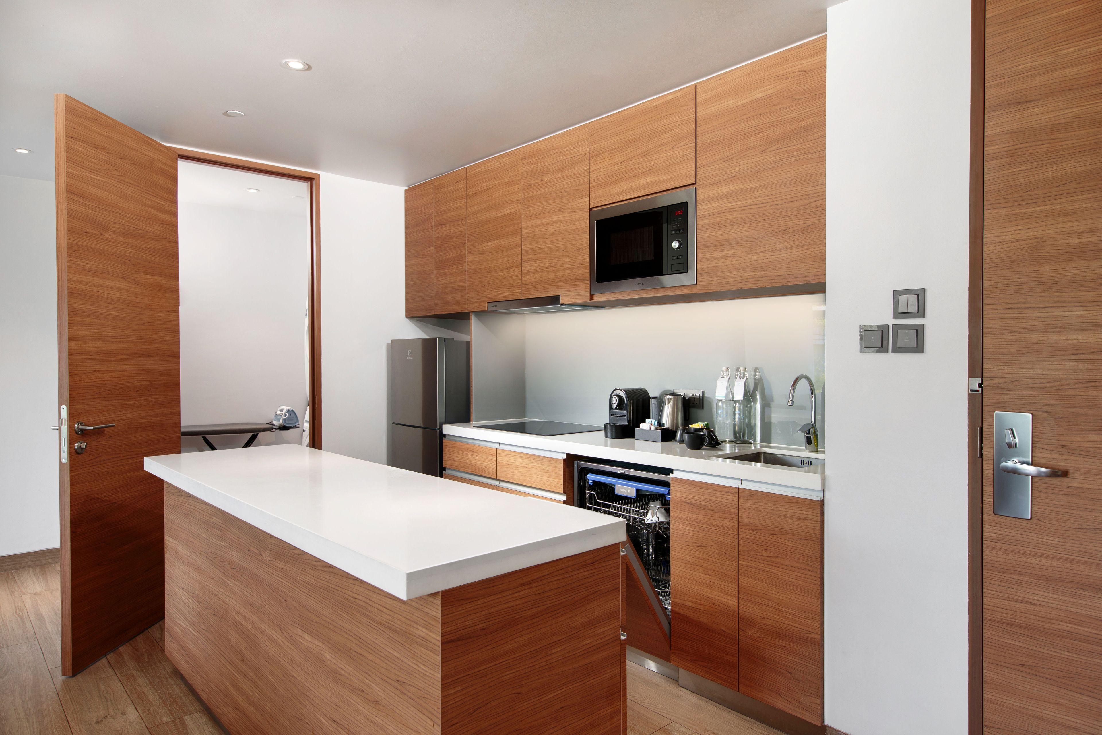 A modern kitchen with wooden cabinetry, a built-in microwave, a stainless steel refrigerator, and a dishwasher.