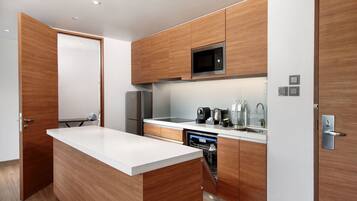 A modern kitchen with wooden cabinetry, a built-in microwave, a stainless steel refrigerator, and a dishwasher.