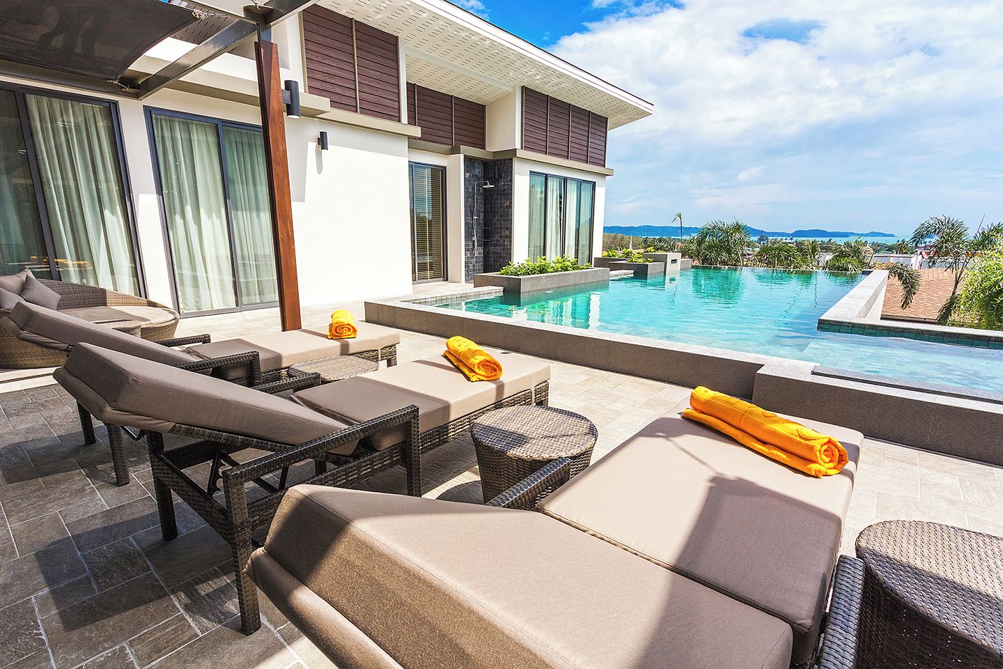 Un área de piscina moderna al aire libre con sillones de descanso y vistas al mar.