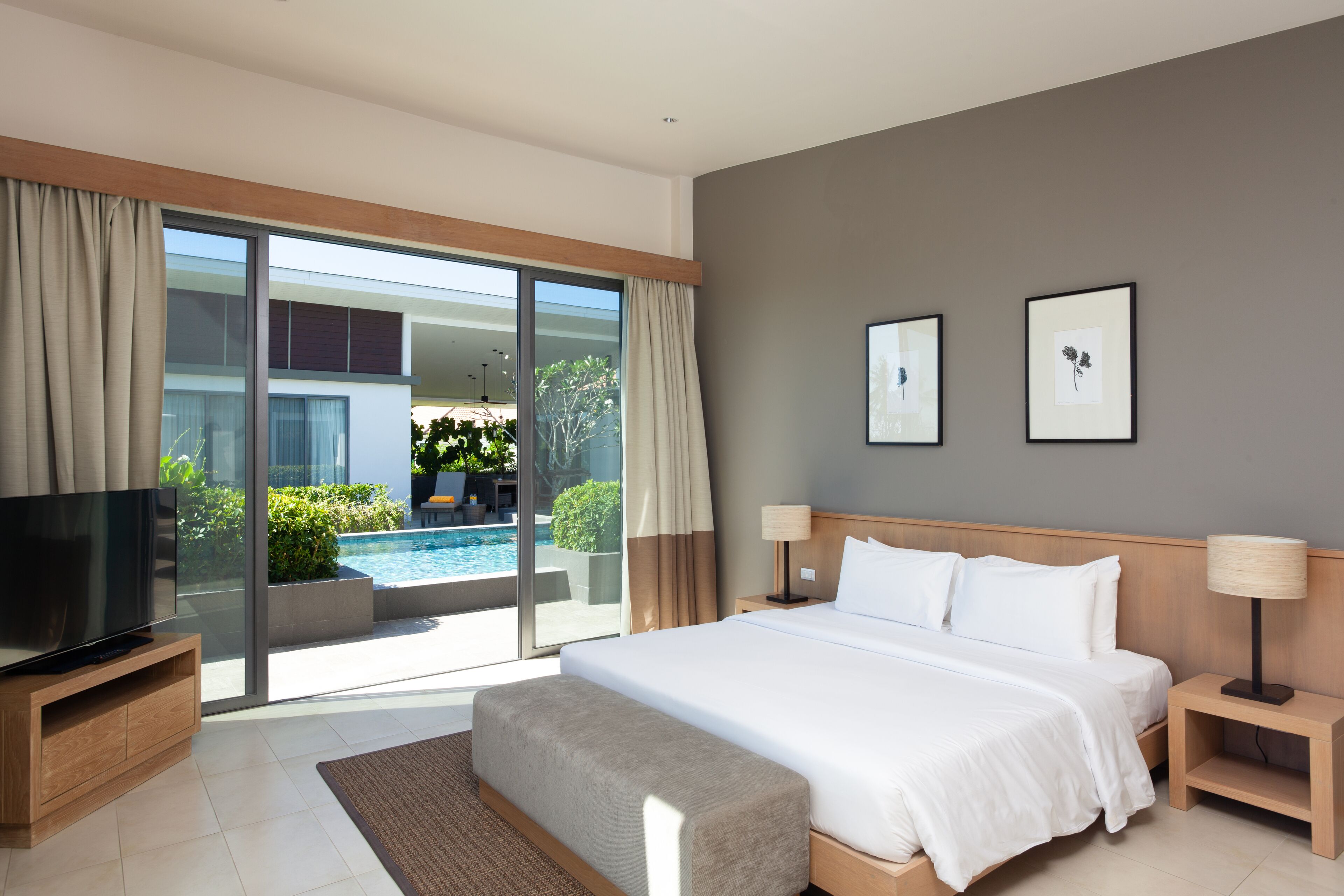 Une chambre d’hôtel moderne avec un grand lit, une télévision et une vue sur une piscine.
