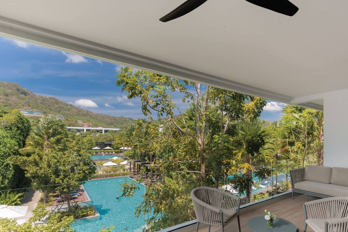 A modern room with a large window overlooking a swimming pool and lush greenery, including a view of distant hills.