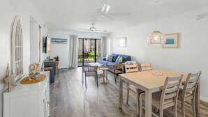 A dining area with a wooden table and chairs, a ceiling fan, and a view of the outdoors. - A short walk to the beach and direct pool access! (Bradenton Beach)