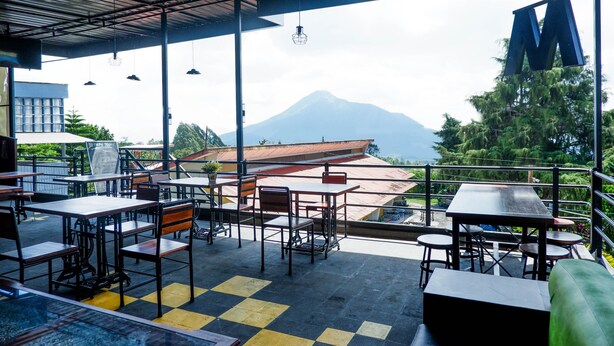An outdoor seating area with tables and chairs, overlooking a mountain. - Collection O 908 Taman Wisata Kopeng (Getasan)