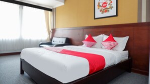 A hotel room with a large bed, a wooden headboard, a framed picture on the wall, and a chair. - Collection O 908 Taman Wisata Kopeng (Getasan)