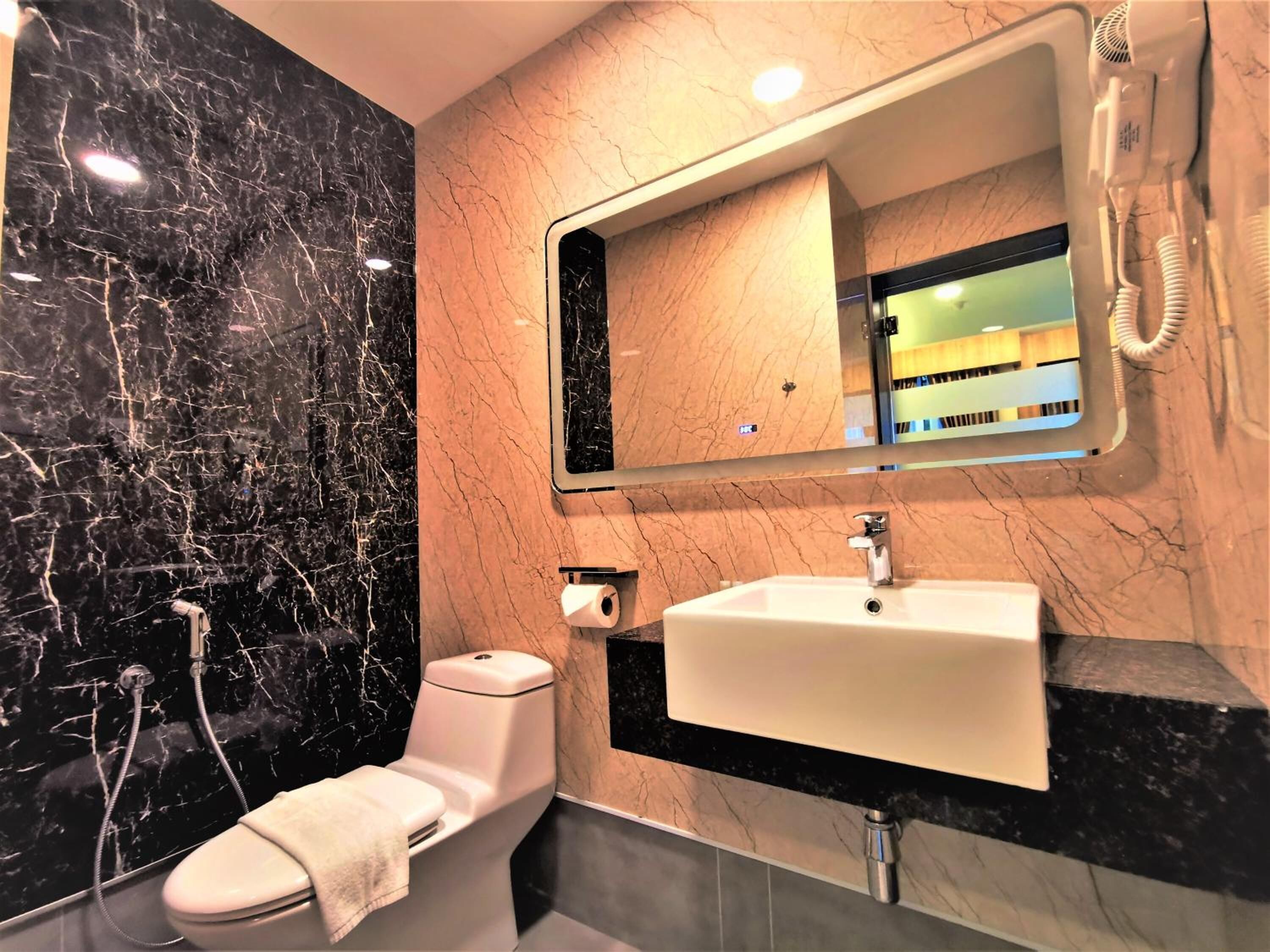 A bathroom with a toilet, sink, and mirror.