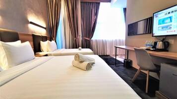Camera d'albergo con due letti, una scrivania, una sedia, una televisione e una finestra con tende.