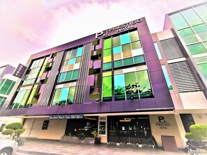 Un moderno edificio de hotel con el nombre 'Prestigo Hotel' exhibido de manera destacada.