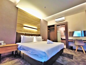 Una habitación de hotel con una cama grande, una mesita de noche y un escritorio con una silla.