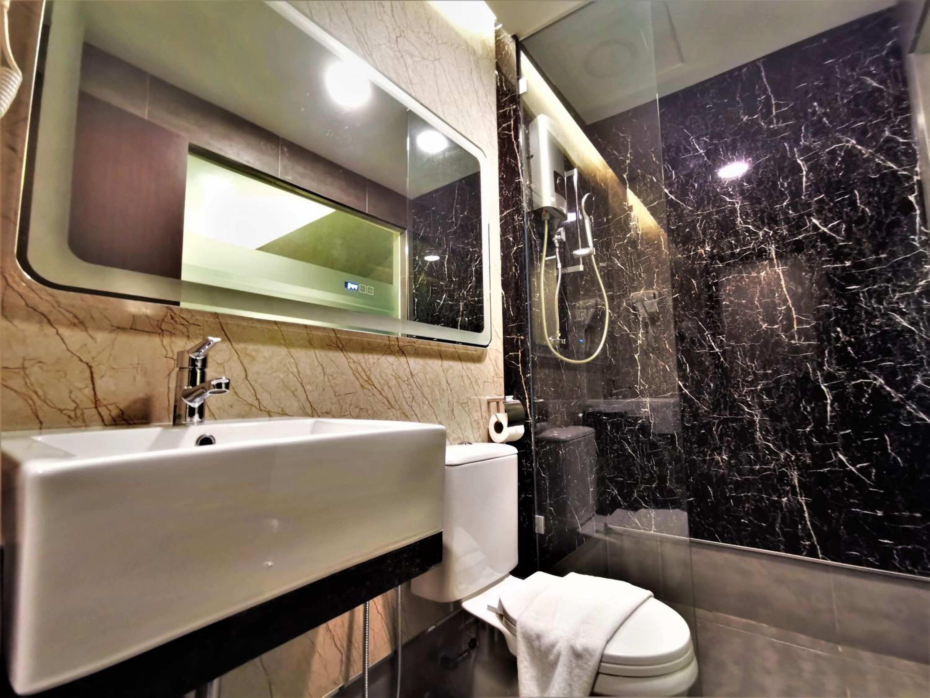 Un baño moderno con lavamanos de mármol, inodoro y zona de ducha con mampara de vidrio.