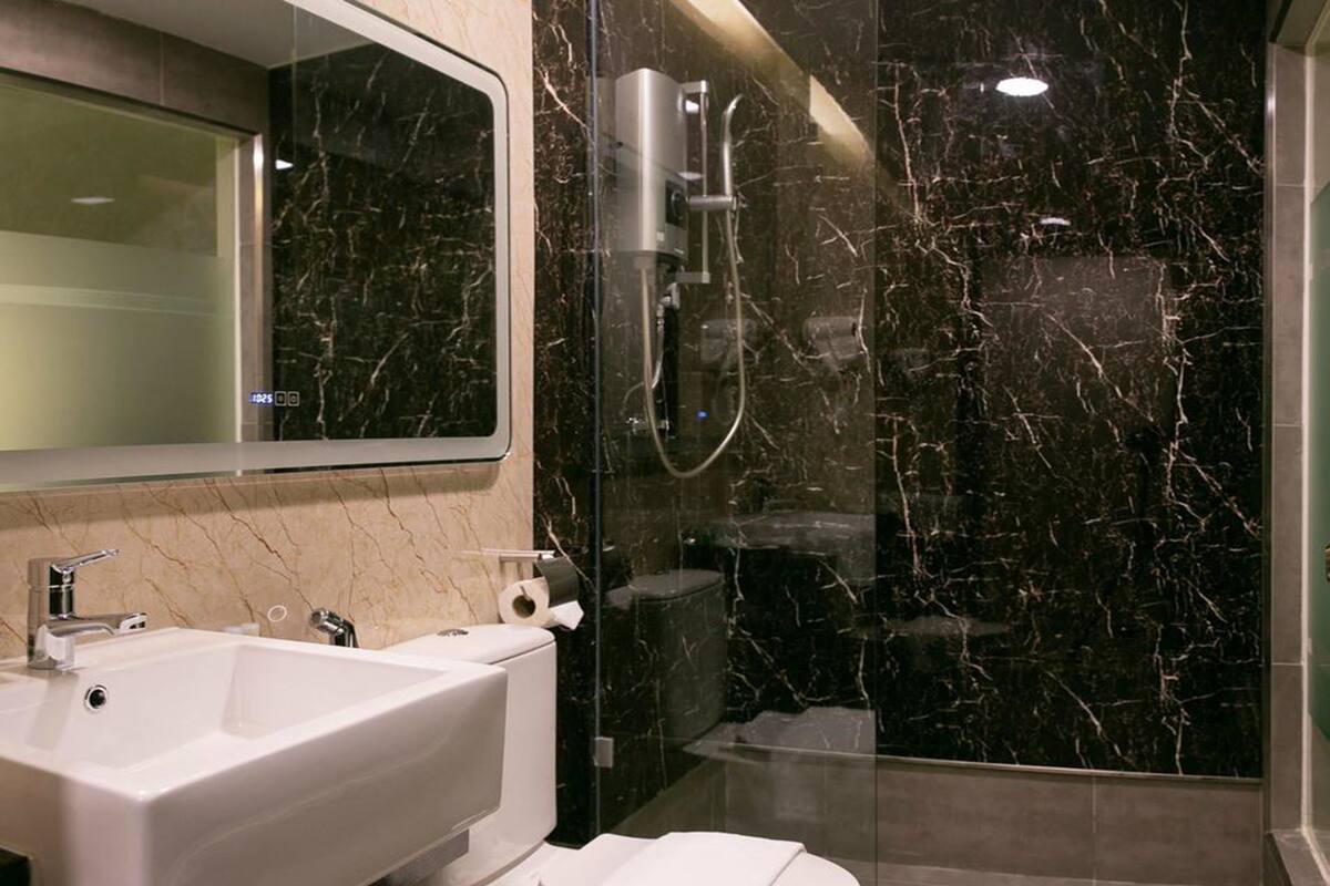 A modern bathroom with a marble sink, toilet, and shower.