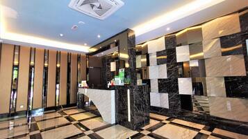 A modern lobby with a checkered floor, a reception desk, and a ceiling vent.