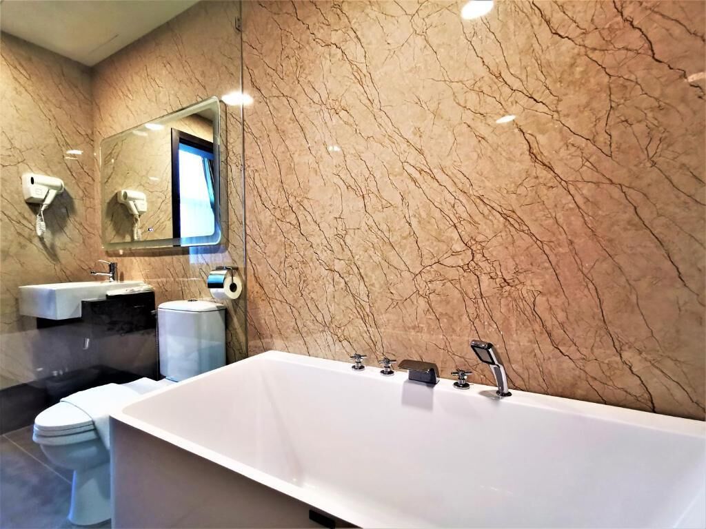 A modern bathroom with a large white bathtub, a sink, and a toilet.