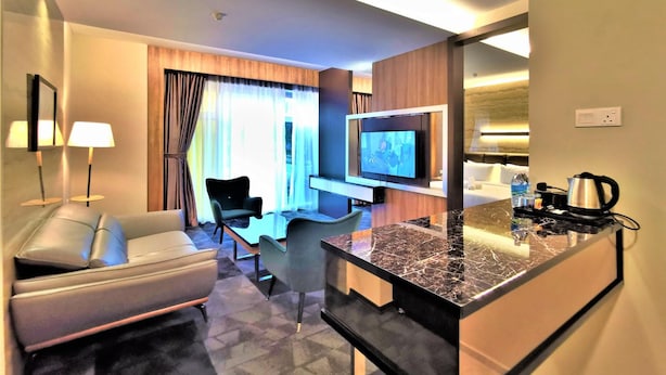 Una habitación de hotel moderna con sofá, televisión, cafetera y una pequeña zona de comedor.