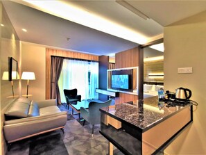 A modern hotel room with a sofa, a TV, a coffee machine, and a small dining area. - Prestigo Hotel (Johor Bahru)