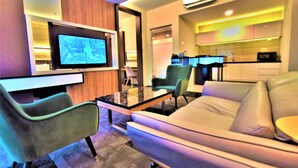Una sala de estar moderna con un sofá, sillas, una mesa de centro, un televisor y una zona de cocina.