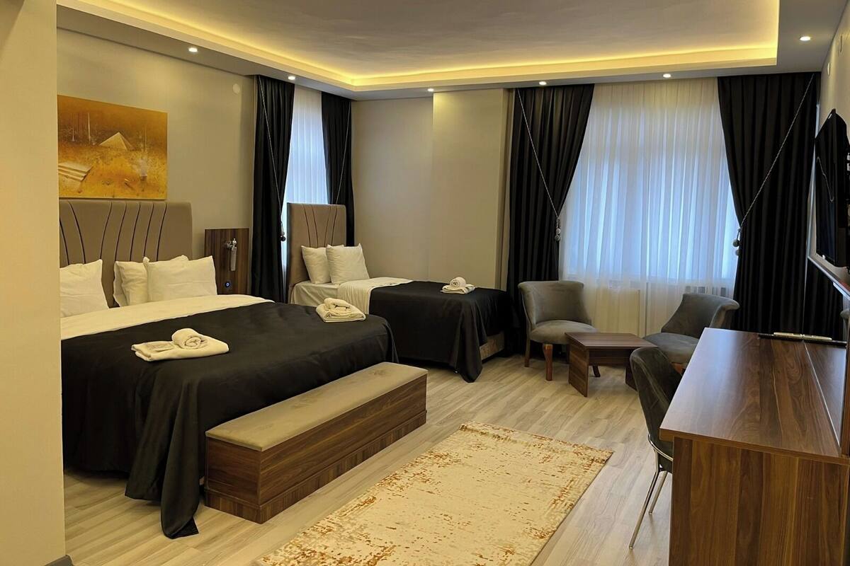 A modern hotel room with two beds, a desk, a chair, and a TV.