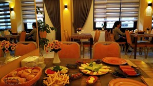 A dining area with tables set for meals, including bread, fries, and various dishes. - Grand Krone Hotel (Cinarcik)