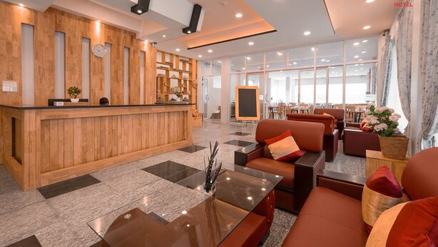 A hotel lobby with a wooden reception desk, seating area with sofas, and a large window offering a view. - Kalaw Garden Hotel (Kalaw)