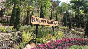 A wooden sign reading "KALAW GARDEN" amidst a well-maintained garden with various plants and flowers. - Kalaw Garden Hotel (Kalaw)