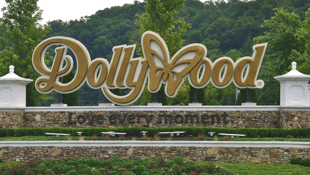 A large sign for Dolly Wood with a stone wall and flower beds in front. - Downtown Gem 💎 -102- Walk to Coffee ☕️ & Anakeesta (Gatlinburg)