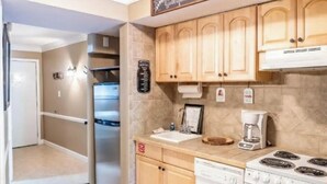 A compact kitchen with wooden cabinets, a refrigerator, a dishwasher, and a stove. - Downtown Gem 💎 -102- Walk to Coffee ☕️ & Anakeesta (Gatlinburg)