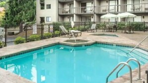 A rectangular pool with a tiled edge, surrounded by a low fence and lounge chairs. - Downtown Gem 💎 -102- Walk to Coffee ☕️ & Anakeesta (Gatlinburg)