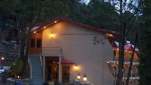 A two-story building with a red roof, a balcony, and a staircase leading to the entrance.