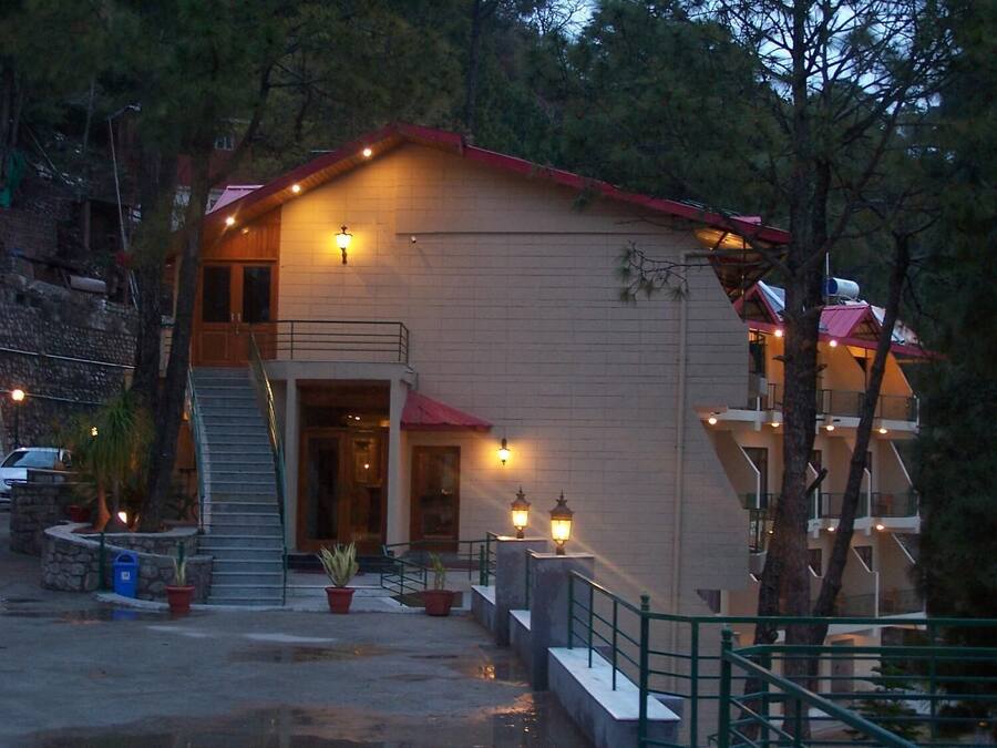 A two-story building with a red roof, a balcony, and a staircase leading to the entrance.