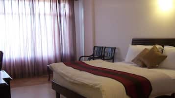 A hotel room with a bed, a desk, a chair, and a window with curtains.