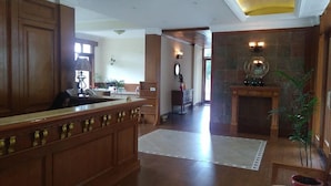 A spacious lobby with a wooden reception desk, a fireplace, and a view of the hallway.