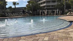 A swimming pool with water fountains, surrounded by lounge chairs and palm trees. - The Newcastle Updated 3BR/2BA ~ Best Location! (Inlet Beach)