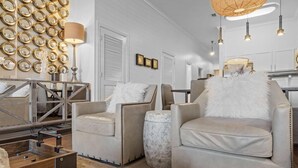 A modern living room with a fireplace, leather armchairs, a coffee table, and a wall of mirrors. - The Newcastle Updated 3BR/2BA ~ Best Location! (Inlet Beach)
