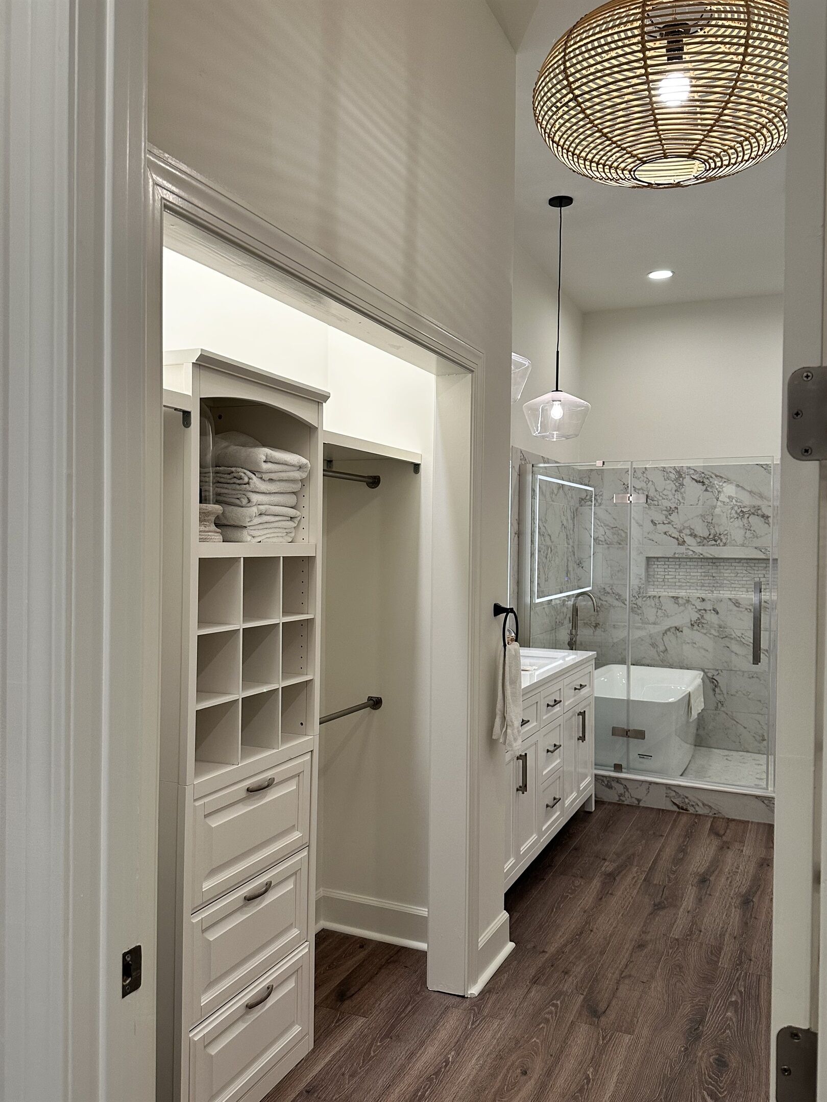 Un baño moderno con ducha a ras de suelo, pared revestida de mármol y un mueble empotrado con estantes y cajones.
